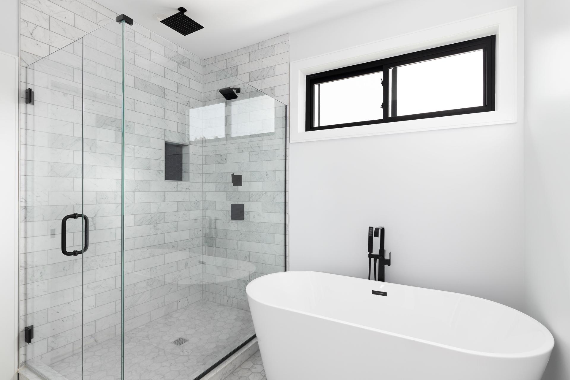 A bathroom's freestanding tub and marble tiled shower.